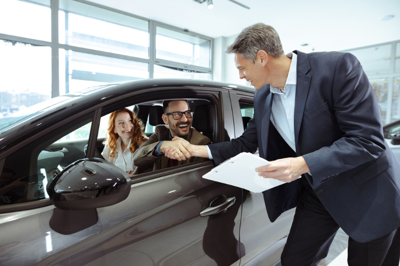 Car Dealer shakes hand with customers.