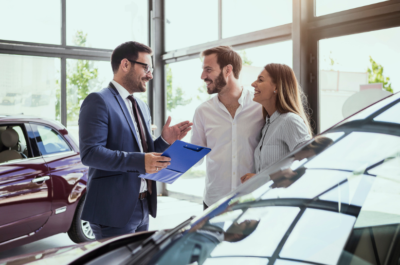 Car Dealer talking to a woman and a man.
