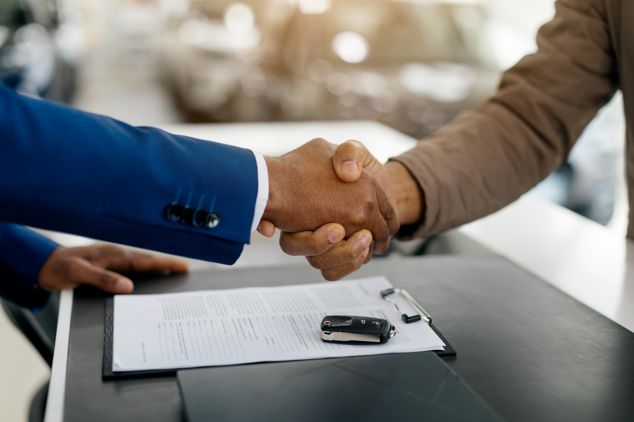Car Buyer And Auto Seller Shaking Hands Buying Automobile In Luxury Dealership Store.