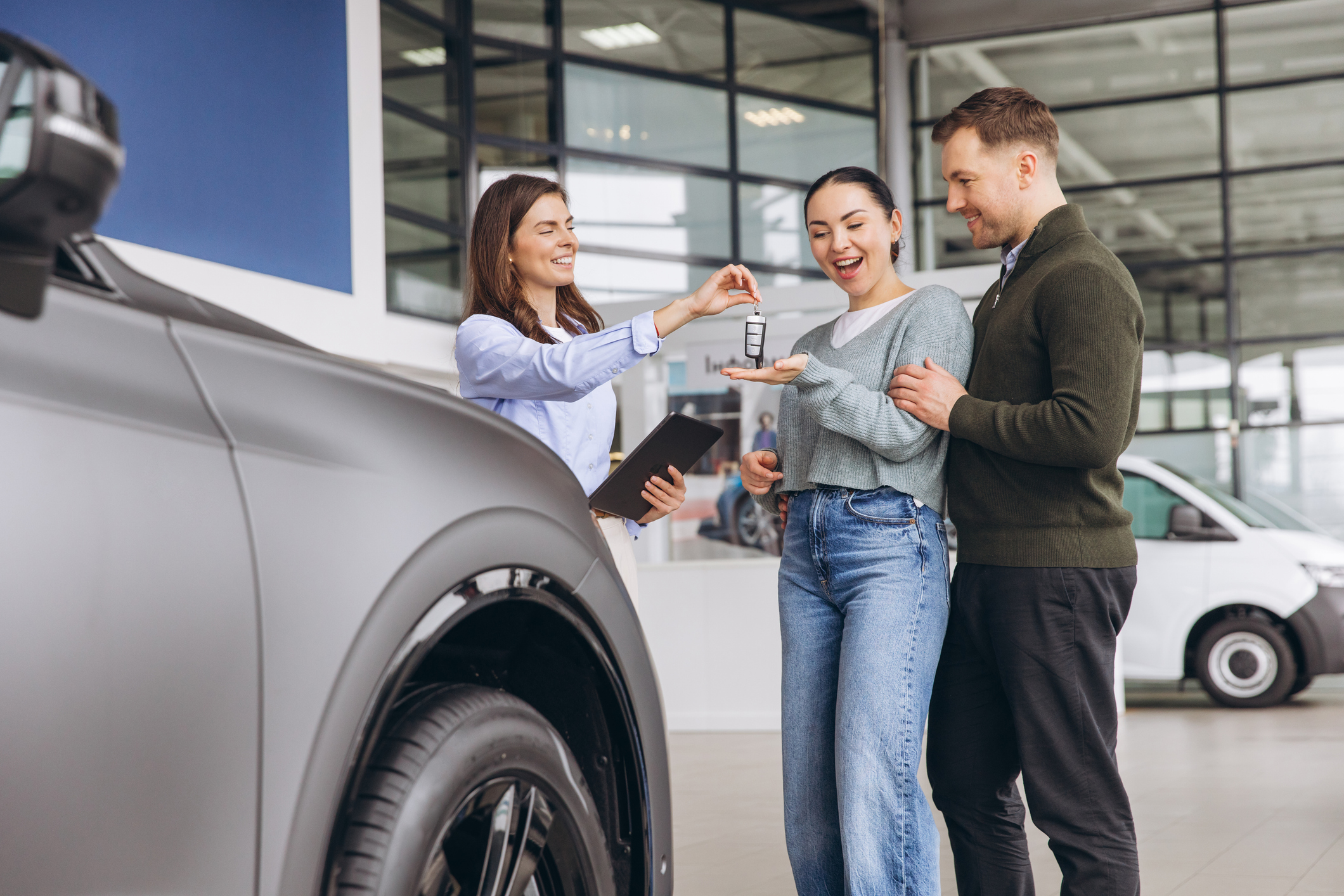 Car salesperson giving keys to excited customers buying a new vehicle, signifying ownership and successful auto retail.