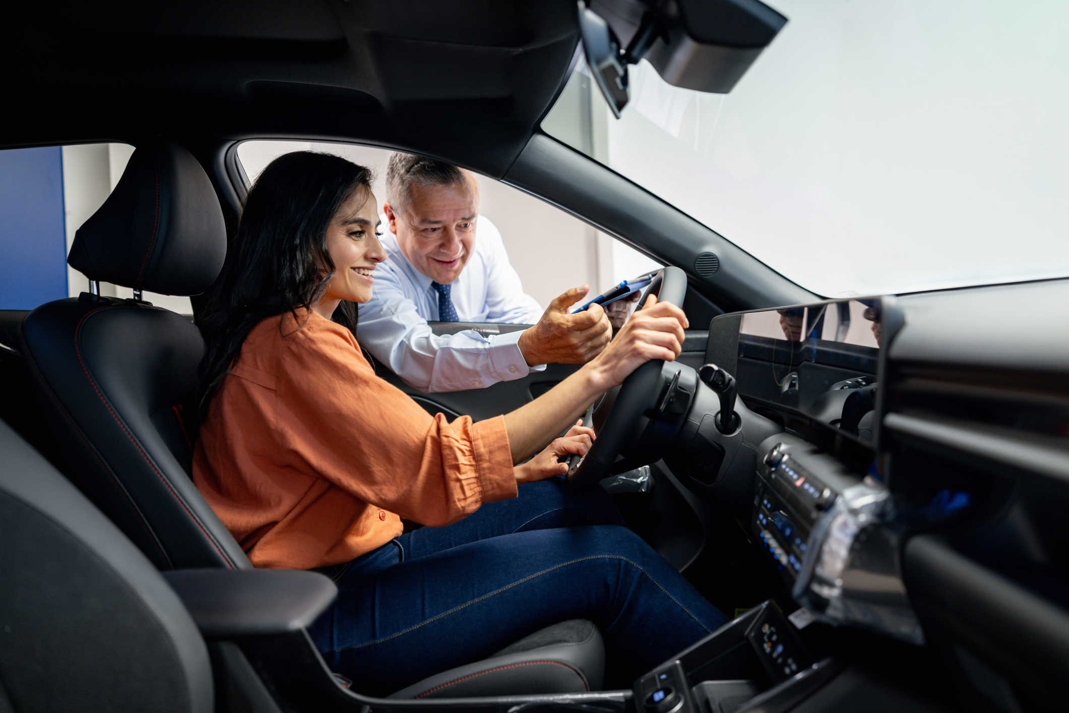 Salesman showing a car for sale to a woman at the dealership